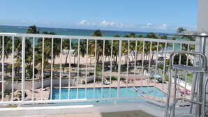 A balcony with a view of a beach, pool, and ocean. - New Oceanfront Dream apartment on the beach of Isla Verde! (Carolina)
