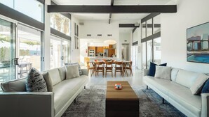 A spacious living area with a sofa, coffee table, and dining table. - Hollywood History Views Saltwater Pool & Spa (Palm Springs)