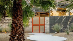 A modern building with a concrete facade, a palm tree, and a circular concrete pathway. - Hollywood History Views Saltwater Pool & Spa (Palm Springs)