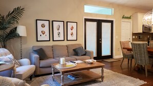 A living room with a beige sofa, a coffee table, and framed botanical prints on the wall.