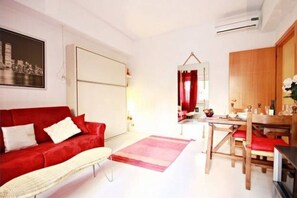 A modern living room with a red sofa, a wooden dining table, and a red and white rug.