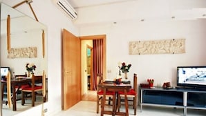 A living room with a wooden dining table, red chairs, a TV, and a large mirror. - ❤Lovely Studio Near Trastevere Jacuzzi, WiFi, Aircon, patio Fully furn Kitchen (Rome)