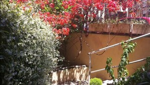 A staircase with a metal handrail, surrounded by flowering plants and a wall. - ❤Lovely Studio Near Trastevere Jacuzzi, WiFi, Aircon, patio Fully furn Kitchen (Rome)