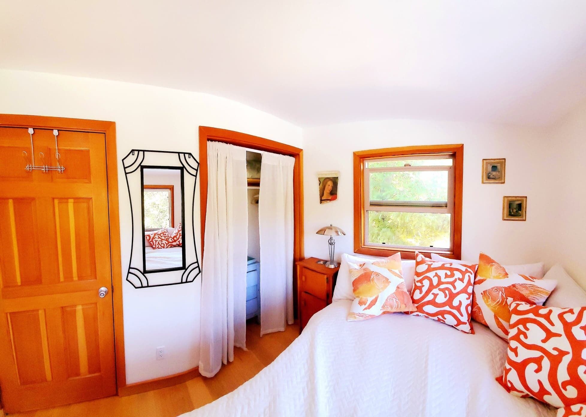 Un dormitorio con cama, mesita de noche, ventana y puerta.