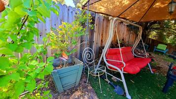 Relax in a serene backyard with a swing chair, garden box, and lush green grass.