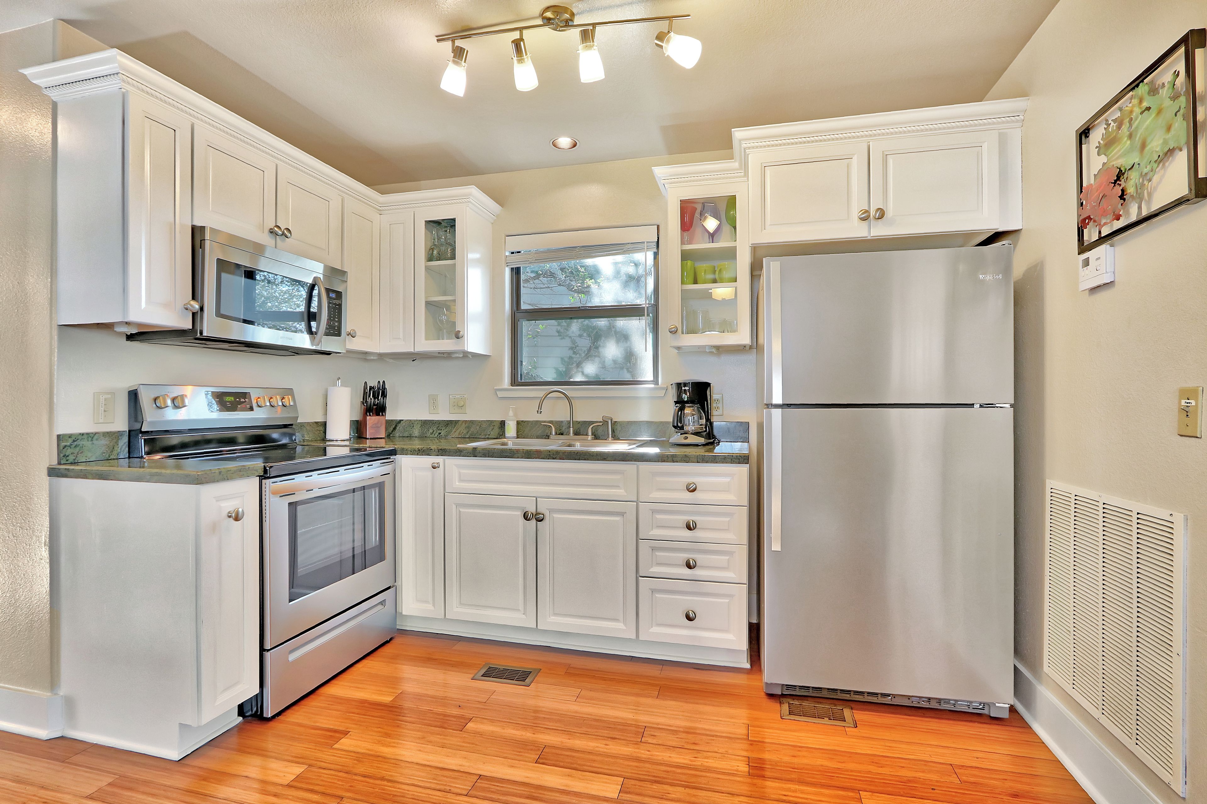 A kitchen with white cabinetry, stainless steel appliances, a window, and a built-in oven.