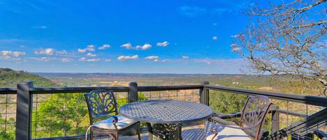 A balcony with a round table and two chairs, overlooking a scenic landscape.