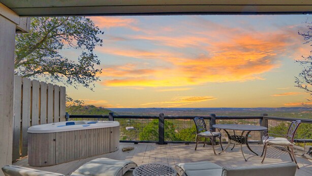 A deck with outdoor seating, a hot tub, and a scenic view of the sunset. - Romantic-amazing Views-Newly Renovated-new Hot Tub-has It All! (Wimberley)