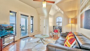 A modern living room with a leather sofa, a glass coffee table, and a flat-screen TV. - Romantic-amazing Views-Newly Renovated-new Hot Tub-has It All! (Wimberley)