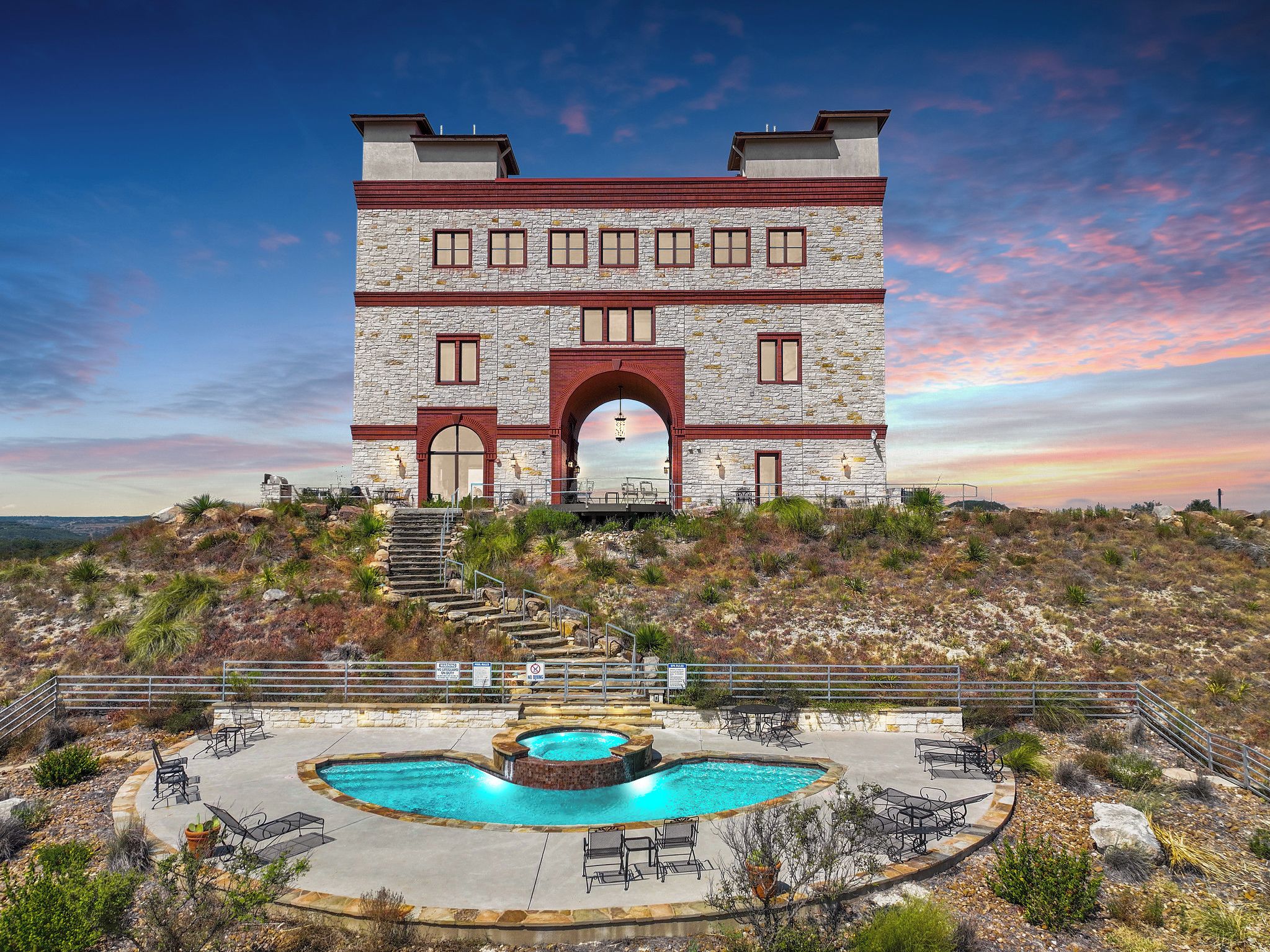 Un edificio de piedra con piscina y zona de estar al aire libre.