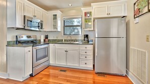 A modern kitchen with white cabinetry, stainless steel appliances, and a window providing natural light. - Romantic-amazing Views-Newly Renovated-new Hot Tub-has It All! (Wimberley)