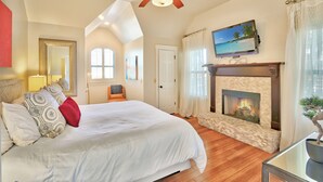 A spacious bedroom with a large bed, a fireplace, and a ceiling fan. - Romantic-amazing Views-Newly Renovated-new Hot Tub-has It All! (Wimberley)