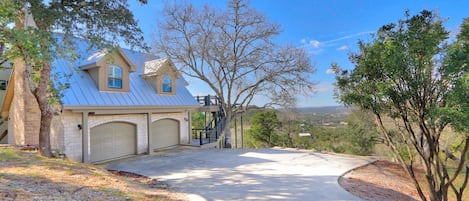 A two-story house with a garage, a covered driveway, and a view of the surrounding landscape.