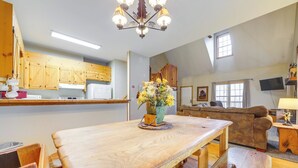 Een ruime woonkamer met een houten eettafel, een bank en een televisie.