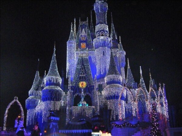 A large, ornate castle with multiple spires and a clock tower, illuminated at night. - Special Rates for Dec 05-26, 2026 - All Rooms Directly Beach Front (Madeira Beach)
