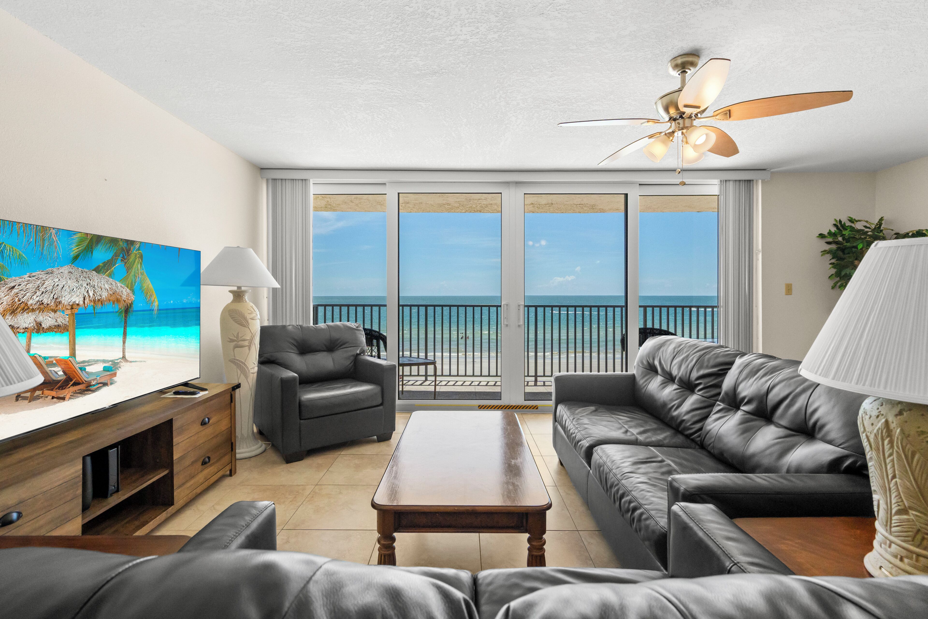 A living room with a sofa, a coffee table, a TV, and a painting of a beach scene.