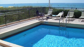 Ein Swimmingpool mit Blick auf den Ozean, umgeben von einem schwarzen Metallzaun.