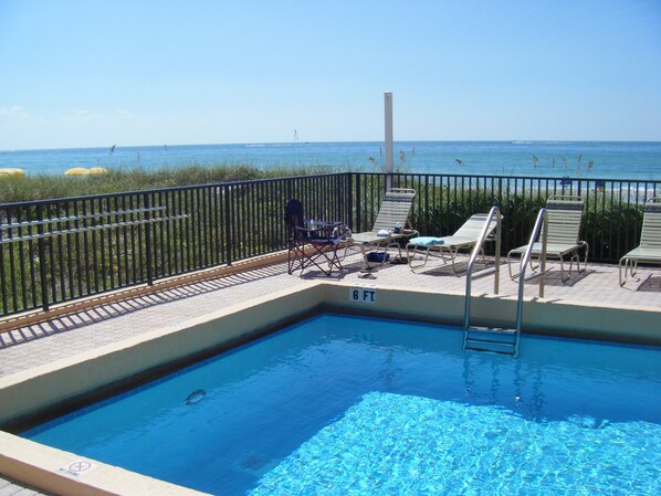 A swimming pool with a view of the ocean, surrounded by a black metal fence.