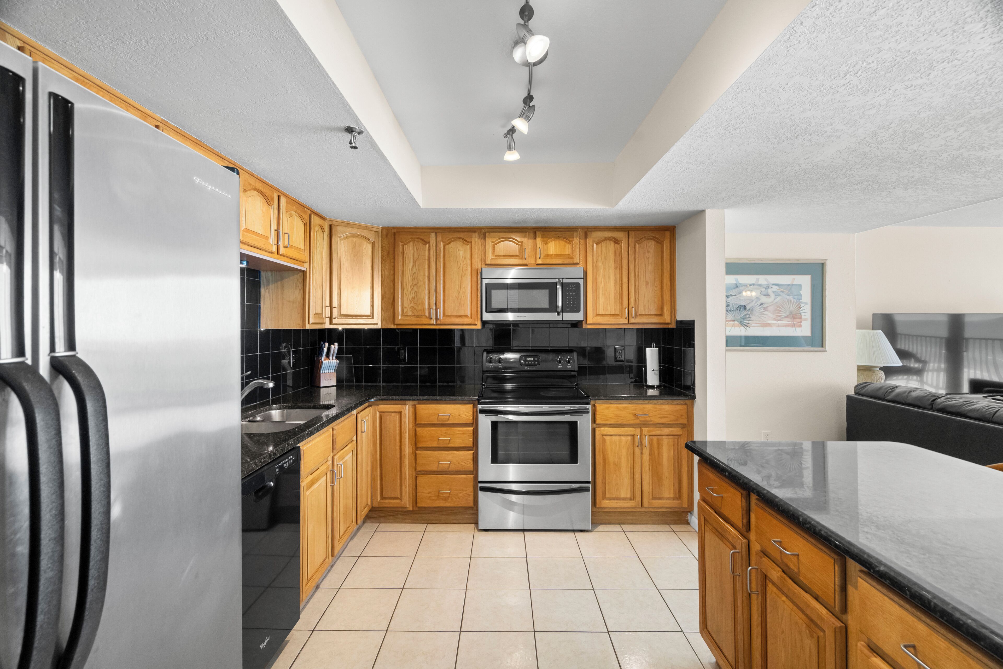 A kitchen with wooden cabinets, a stainless steel refrigerator, a microwave, and an oven.