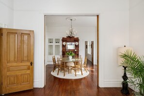 Un comedor con una mesa redonda, sillas, una araña y un armario de madera.
