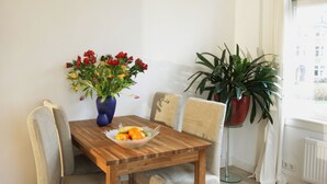 A dining area with a wooden table, four chairs, a vase of flowers, and a bowl of fruit. - Private Apartment in Good Area (Amsterdam)