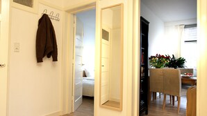A spacious living area with a wooden floor, a coat rack, and a dining area with chairs and a table. - Private Apartment in Good Area (Amsterdam)