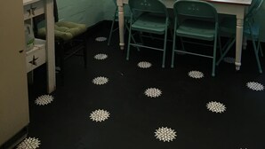 Une petite cuisine avec une table et des chaises, un réfrigérateur et une fenêtre avec des stores.