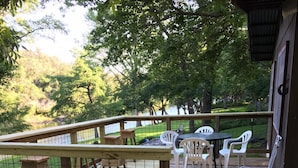 Une terrasse en bois avec un chemin de pierre menant à un espace détente équipé de chaises en plastique et d’une table.