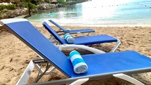 Un área de descanso en la playa con tumbonas y toallas azules.