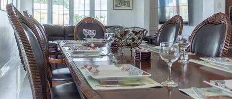 A dining room with a long table set for six, surrounded by upholstered chairs.