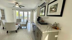Una cocina moderna con encimera de mármol, ventilador de techo y vistas al exterior a través de amplias ventanas.