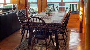 A wooden cabin interior with a dining table, chairs, and a sofa. - Couples Dream Getaway! Unobstructed Views of the Smoky Mountains National Park! (Sevierville)