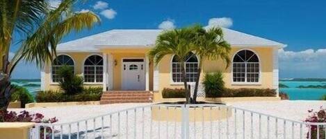 A two-story house with a white exterior, a front porch, and a view of the ocean.