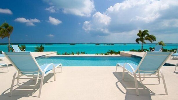 Ein Poolbereich mit Liegestühlen und Blick auf das Meer.