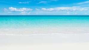 Ein Strand mit klarem türkisblauem Wasser und weißem Sand.
