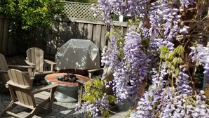 Un espace patio aménagé avec du mobilier d’extérieur, un barbecue et des glycines.