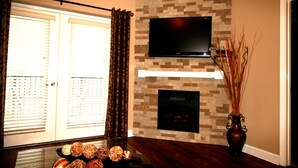 Un soggiorno con camino, una TV a schermo piatto montata a parete e un vaso decorativo con rami.