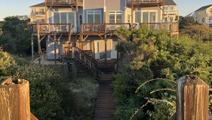 Una casa de varios pisos con un balcón y escaleras que conducen a una terraza de madera.