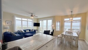 Amplia sala de estar con una isla grande, una mesa de comedor y vista al océano.