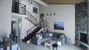 Amplia sala de estar con un sofá seccional gris, una mesa de centro de madera y una chimenea de piedra.