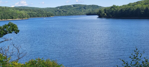 A large body of water surrounded by forested hills.