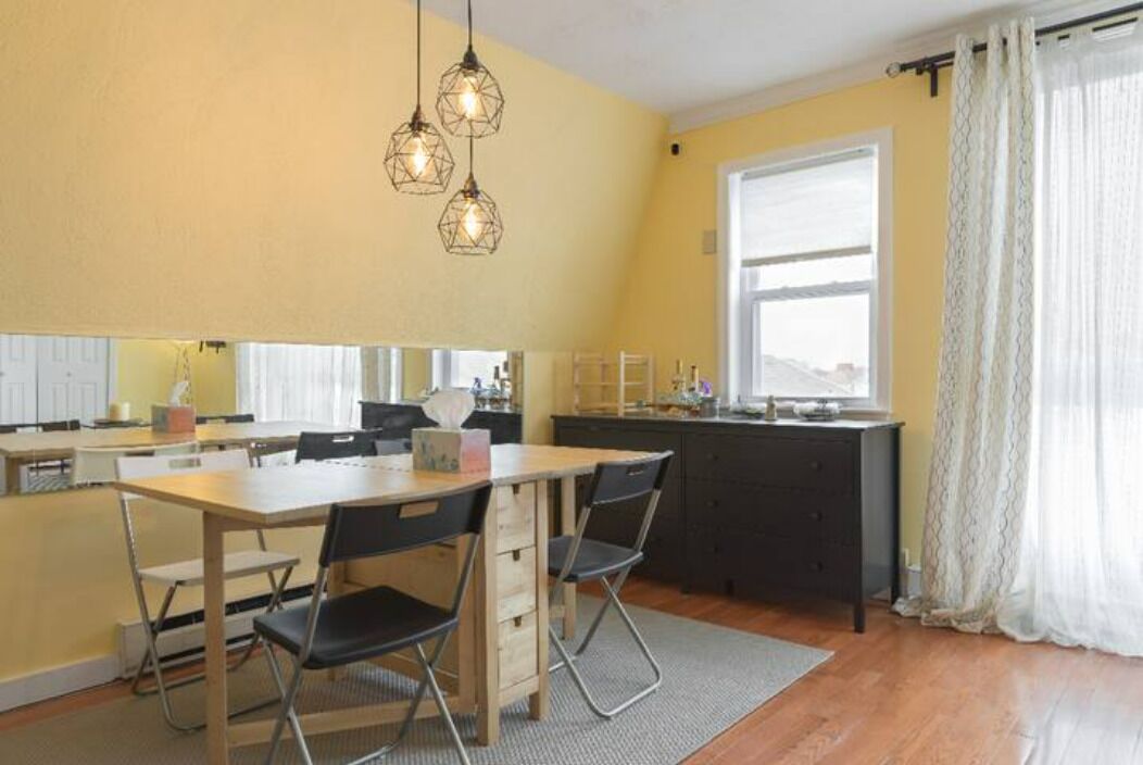 A compact kitchen with a dining table, chairs, and pendant lights.