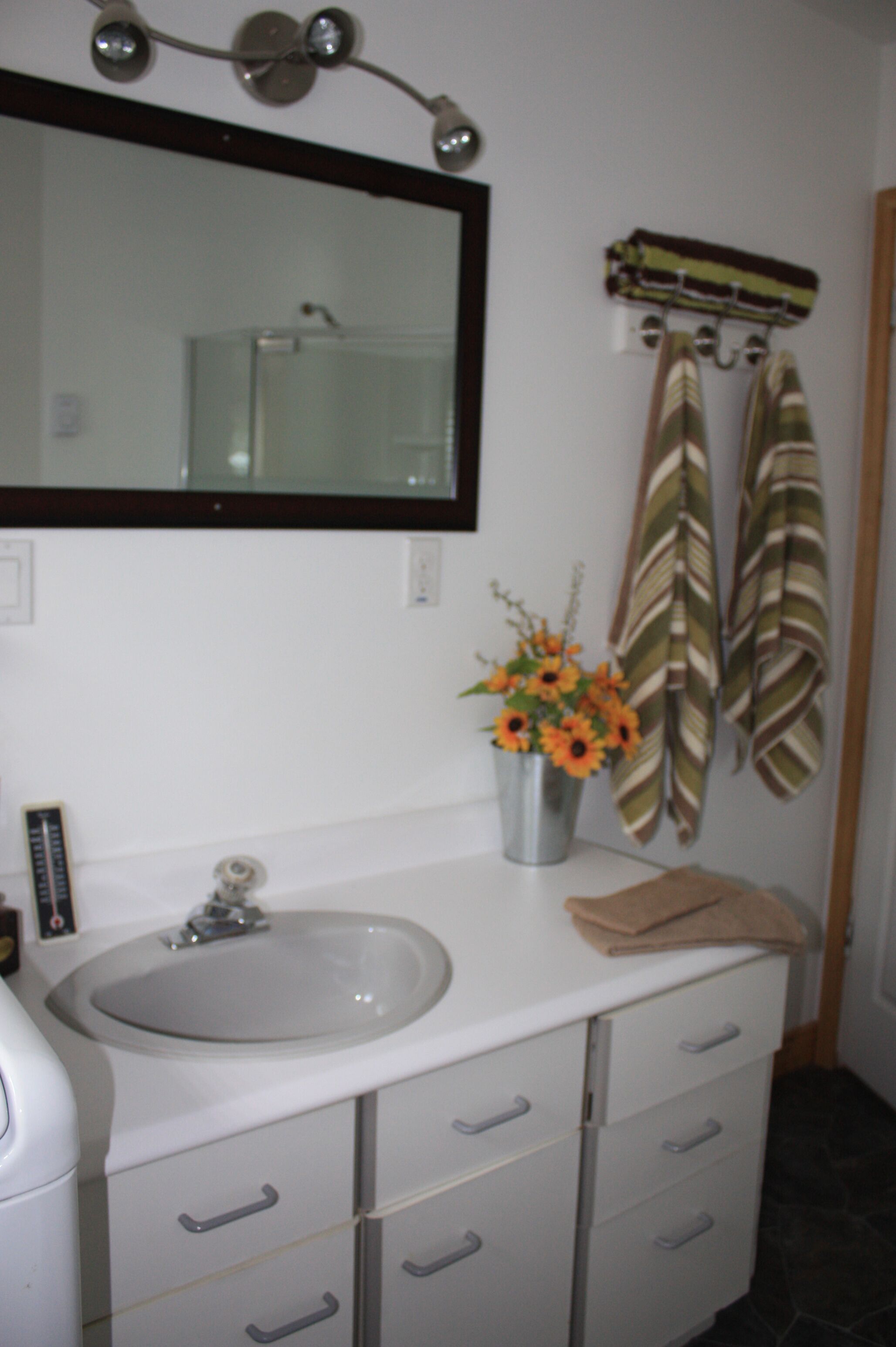 Une salle de bain avec un lavabo blanc, un miroir et des serviettes à rayures accrochées au mur.