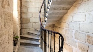 A stone staircase with a metal railing leading to a landing.