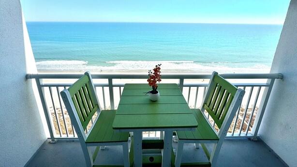 A balcony with a view of the ocean, a green table, and two chairs. - 💎ISLAND TIME Dolphin Shack; Gorgeous Direct Oceanfront Balcony King Luxury Bed (Myrtle Beach)