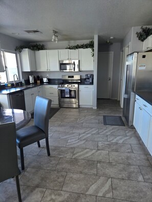 A modern kitchen with white cabinets, stainless steel appliances, and a dining area with a glass table and chairs.
