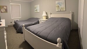 Een slaapkamer met twee enkele bedden, een nachtkastje met een lamp, een radiator en kunst aan de muren.