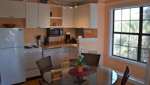 A kitchen with white cabinets, a microwave, a stove, and a dining table with chairs.