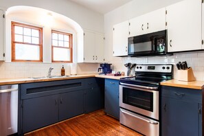 Una cocina con armarios blancos, una estufa de acero inoxidable y un microondas.