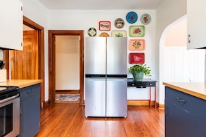 Una cocina con un refrigerador de acero inoxidable, armarios de madera y piso de madera.